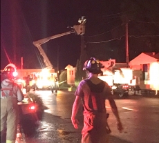 Lake City firefighters maintain a perimeter at the entrance to Marina Point while city public works employees work to restore power Thursday night.